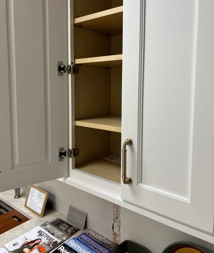 kt-cabinetry-showroom Example of a Connecticut custom cabinet offered by Kitchen Traditions. Features include maple shelving, neutral white exterior, brass handles, and stainless steel hinges.