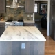 Bright kitchen featuring a grey island with a marble countertop, introducing sleek, low-maintenance design trends.