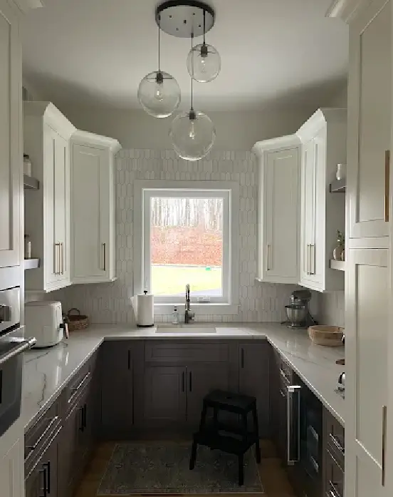 kitchen-remodel-benefits-modern-functional-design Compact U-shaped kitchen renovation with two-tone cabinets, picket tile backsplash, and glass globe pendants over the sink window.