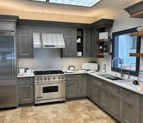 kitchen-remodel-finished-modern-happy-home Gray shaker kitchen with professional six-burner range, shiplap backsplash, and open shelving on display at the Kitchen Traditions design showroom in Danbury CT.
