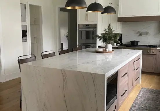 Kitchen Traditions Connecticut remodel showcasing a quartzite waterfall island counter with bold natural veining and wood flooring.