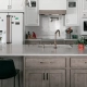 Remodeled Connecticut kitchen island with pale gray engineered stone counter, taupe wood cabinets, gold fixtures, and pendant lighting.