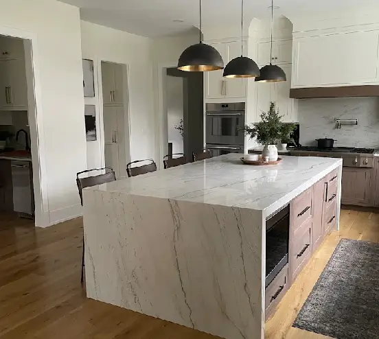 custom-kitchen-cabinet-planning Waterfall island in white veined stone with light wood drawer cabinets, a built-in microwave, and black dome pendants, a two-tone custom kitchen.
