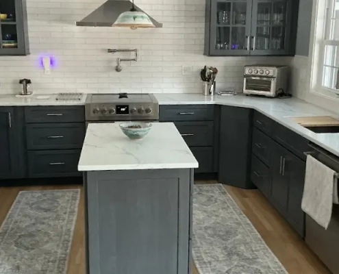 U-shaped kitchen with charcoal shaker cabinets, glass-front uppers, white marble-look counters, and a small island, showing custom cabinets in CT.